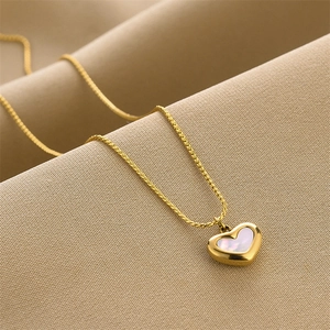 Gold heart necklace with iridescent mother of pearl inlay on beige fabric background