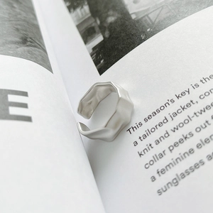 Macro shot of minimalist silver ring featuring irregular matte concave surface and waves