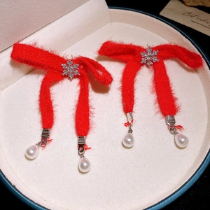 Macro view of Christmas red bow earrings with snowflake zircons and pearl drop details