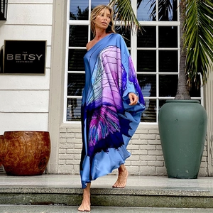 Detail eines blauen One-Shoulder-Maxikleides mit Satin-Finish und Schmetterlingsdruck
