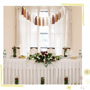 Bohemian tassel garland with brown and beige fringes hanging over a wedding banquet table