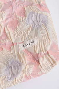 Macro shot of 3D floral jacquard fabric and sewn H&R BAG label on a cosmetic pouch