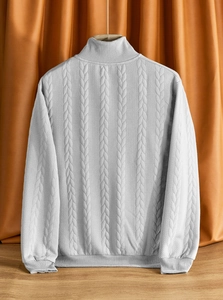 Dettaglio maglione grigio in maglia con trama a trecce classica e bordo inferiore a coste