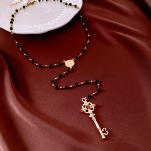 Détail macro du pendentif clé dorée vintage avec pierre œil de tigre et perles noires