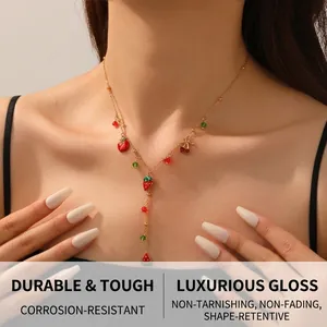 Détail d'un collier doré avec pendentifs de fruits comme la fraise et la pastèque