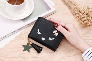 Detail of black cat coin purse with pink rhinestone bow and tassel charm on wood surface