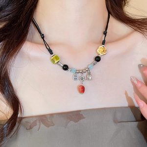 Detail of retro ceramic beaded necklace featuring silver lucky charm on black braided cord