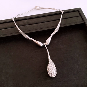 Détail macro de la chaîne argentée texture lave et grand pendentif goutte en zircon