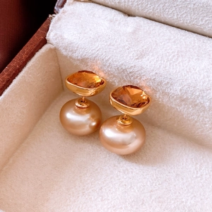 Detail of 18K gold-plated double-pearl earrings with amber crystal in a velvet box