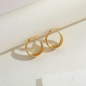 Detail view of high-polish gold hoop earrings on minimalist stone display stand