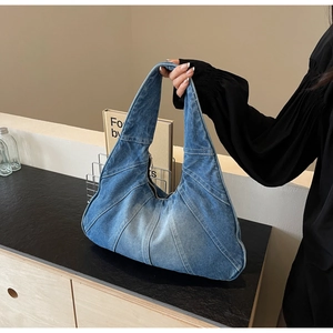 Détail du sac hobo en jean bleu avec coutures contrastées et finition délavée tendance