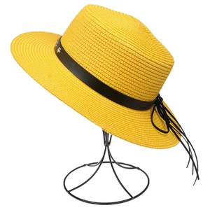 Close-up of a straw sun hat with black band and star studs on a metal display stand