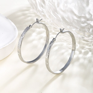 Detail view of silver chain texture large hoop earrings with engraved star patterns