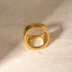 Detailed close-up of a 18k gold plated hollow square ring on a white marble surface