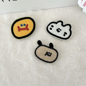 Close-up of three cute plush embroidered patches with cartoon animal designs and soft textures