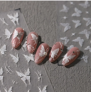 Detailed 3D white butterfly nail decals with embossed texture on pink shimmer nails