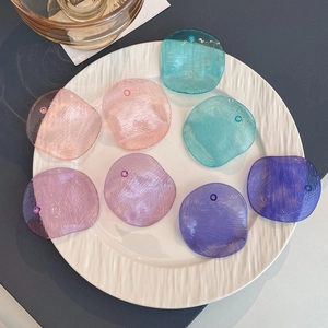 Colorful oval acrylic drop earrings with geometric texture in a white ceramic dish