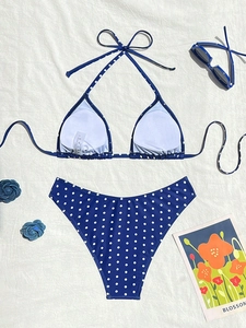Dettaglio flat lay del bikini blu a pois bianchi con eleganti accessori da spiaggia