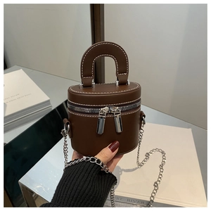 Gros plan d'un mini sac cylindrique marron vintage avec chaîne argentée et fermetures