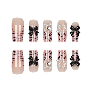 Pink press-on nails with black zebra and leopard prints, featuring bows and heart charms