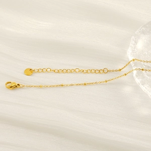 Close-up of golden stainless steel beaded chain necklace with lobster clasp and extender