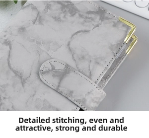 Detail of marble pattern PU leather binder with gold metal corners and durable stitching