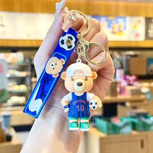 Detail of a cartoon bear keychain in a blue football jersey with a silicone strap