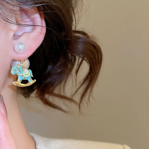 Detailed macro view of horse-shaped drop earrings with pearls and colorful enamel dots