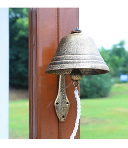 Close-up of vintage cast iron garden doorbell with aged bronze finish and pull rope