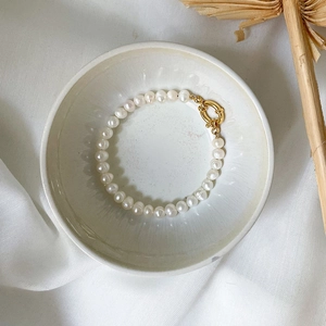 Baroque freshwater pearl bracelet with golden OT toggle clasp on a white ceramic plate