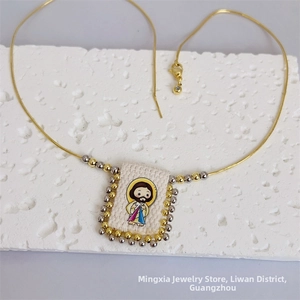 Close-up of 18K gold plated snake chain with a cartoon Jesus pendant and beaded border