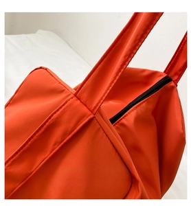 Detail shot of sturdy double stitching on orange oxford fabric gym bag with black zipper