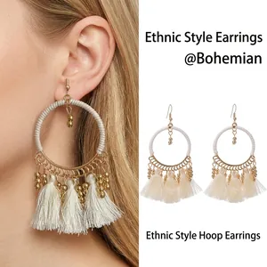 Detail of bohemian round hoop earrings featuring white cotton wrap and beaded tassels