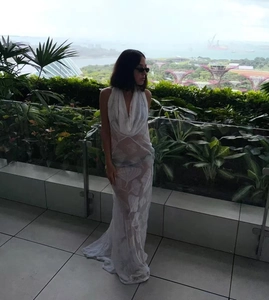 Close-up of white semi-transparent maxi dress with leaf patterns and deep V-neckline