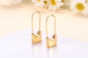 Macro shot of 18k gold plated U-shape earrings with geometric solid drop pendants