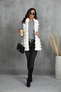 Gilet long en fausse fourrure blanche chic porté avec un jean noir et un sac à bandoulière