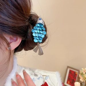 Detail of fish-shaped hair clip with blue scales on elegant dark brown hair updo