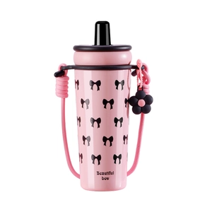 Pink stainless steel straw cup with black bow patterns and a woven shoulder strap