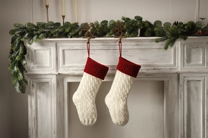 Close-up of cable knit Christmas stockings in white and red hanging on a classic fireplace