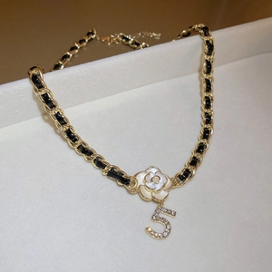 Detailed shot of camellia flower and rhinestone number 5 charms on leather chain