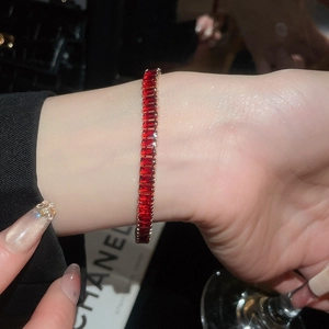 Detailed view of an 18k tennis bracelet featuring rectangular red rubies on a wrist