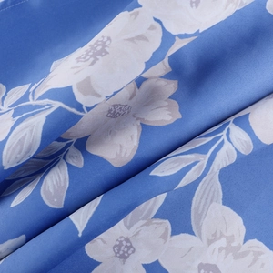 Detailed macro view of white floral print on dark blue draped textile fabric