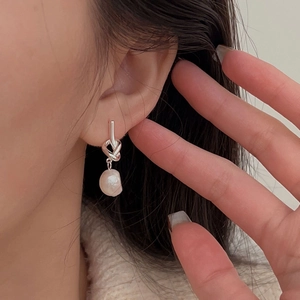 925 silver knot earrings with white baroque pearl hanging on a model's ear