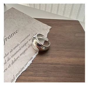 Close-up of polished silver wide ring on vintage paper and dark wood background