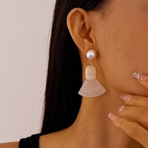Dettaglio di orecchini vintage con perle e pendenti a ventaglio in resina su modella