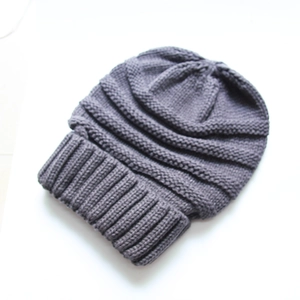 Detail of grey knitted winter beanie featuring thick ribbed texture and wide folded cuff