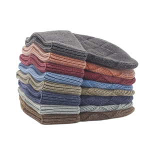 Detail of stacked ribbed knit beanies showing thick core-spun yarn and textured cable patterns