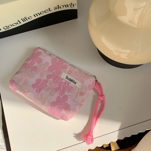 Close-up of pink floral fabric pouch with zipper closure and braided wrist strap