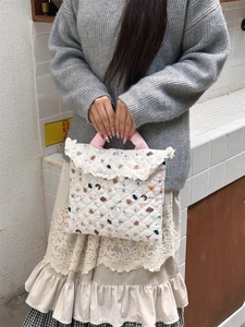 Detailed close-up of quilted cartoon laptop sleeve with white lace edges and floral bear pattern