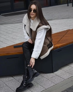 Outdoor street style view of a brown fleece vest paired with stylish black buckle boots